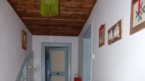 A hallway with a wooden bench, a red bag, and a green hanging light fixture. - MASO PINTERATO - Narciso apartment (Cavalese)