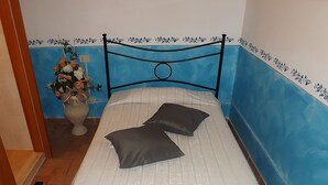 Ein kleines Bett mit Metallgestell, weißer Bettwäsche und zwei Kissen.