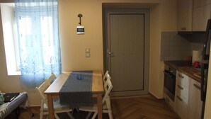 Eine kleine Küche mit Esstisch, Stühlen, einem Kühlschrank und einer Tür, an deren Wand ein Schlüssel hängt.