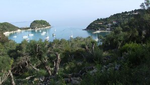 Eine Küstenlandschaft mit Booten vor der Küste, umgeben von üppiger Vegetation und Hügeln.