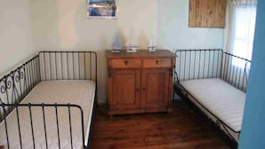 A room with two metal bunk beds, a wooden cabinet, and a small table with decorative items.