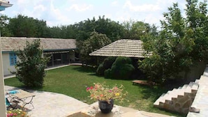 A courtyard with a covered seating area, a flower pot, and a stone staircase.