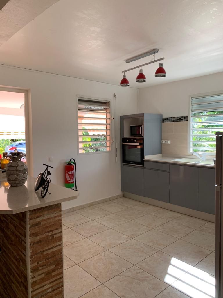 Una cocina moderna con armarios grises, horno empotrado y ventana con persianas.