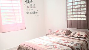 A bedroom with a bed, curtains, a wall quote, and a hanging light fixture. - F3 FROM 2 TO 6 BEDS 10 MN BEACH BOURG DE SAINTE ANNE (SAINTE ANNE)