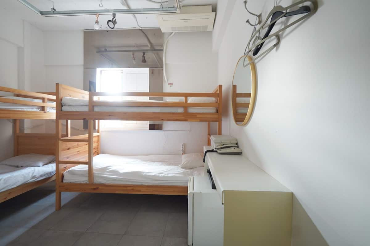 A bunk bed room with a desk and a mirror.
