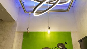 Un techo moderno con lámparas circulares y una pared verde con un cuadro abstracto grande.