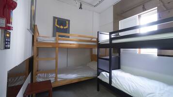 A bunk bed room with a small wooden stool, a wall clock, and a poster.