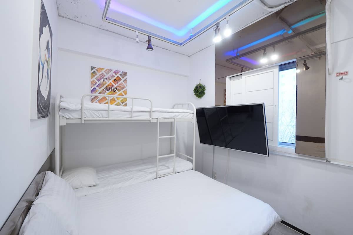 A bunk bed room with a TV, a window, and a wall art piece.