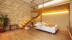 A modern bedroom with a wooden floor, a brick wall, a bed, a small table, a potted plant, and a staircase.