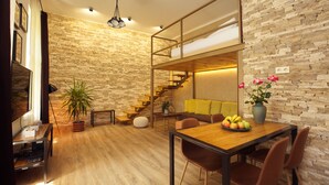 A modern interior with a wooden dining table, brown chairs, a staircase, and a brick wall.