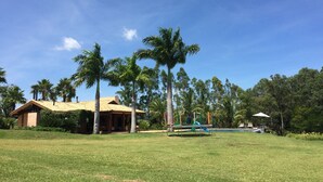A house with a tiled roof, surrounded by a grassy lawn and palm trees. - BEAUTIFUL PROPERTY IN PORTO FELIZ (Porto feliz)