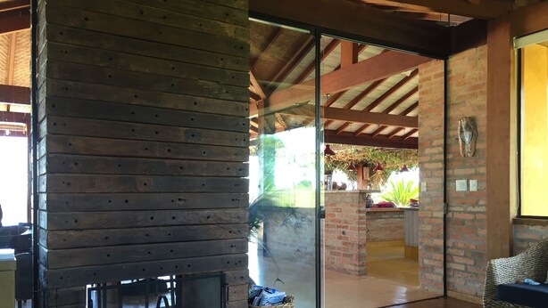 A rustic interior with a wooden fireplace, wicker furniture, and a glass door leading outside. - BEAUTIFUL PROPERTY IN PORTO FELIZ (Porto feliz)