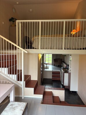 Un intérieur à plusieurs niveaux comprenant un escalier, un coin cuisine et un lit avec vue.