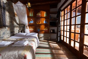 A room with a bed, a wooden cabinet with colorful artwork, and large windows. - one bedroom house with terrace-split level (ELOUNDA CRETE)