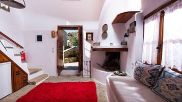 Cozy living area with a sofa, fireplace, and staircase.