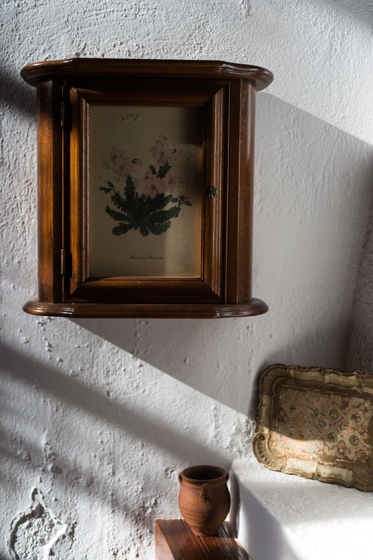 Ein gerahmtes Bild mit floralem Muster an einer strukturierten Wand.