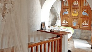 Een kamer met een houten trap, een bed met baldakijn, en een muur versierd met maritieme decoraties.