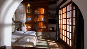 Een slaapkamer met een bed, een houten kast met decoratieve panelen, een televisie en een raam met uitzicht.
