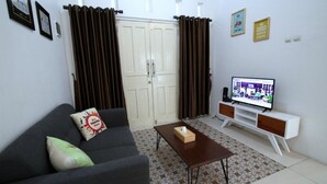 A living room with a sofa, a coffee table, a TV on a stand, and a wardrobe.