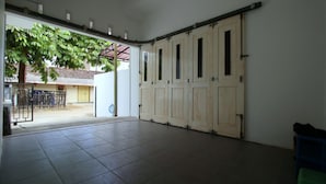 A spacious room with a large sliding door, tiled floor, and a view of a building with a tree outside.