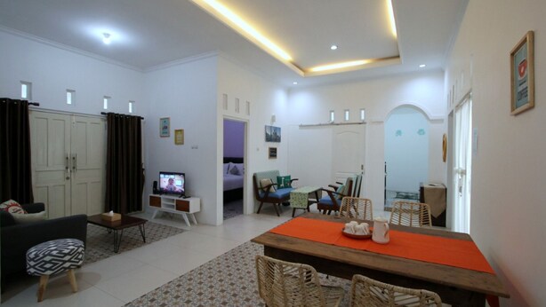 A modern living room with a sofa, TV, dining table, and chairs.