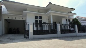 A two-story house with a covered porch, a garage, and a black metal fence.