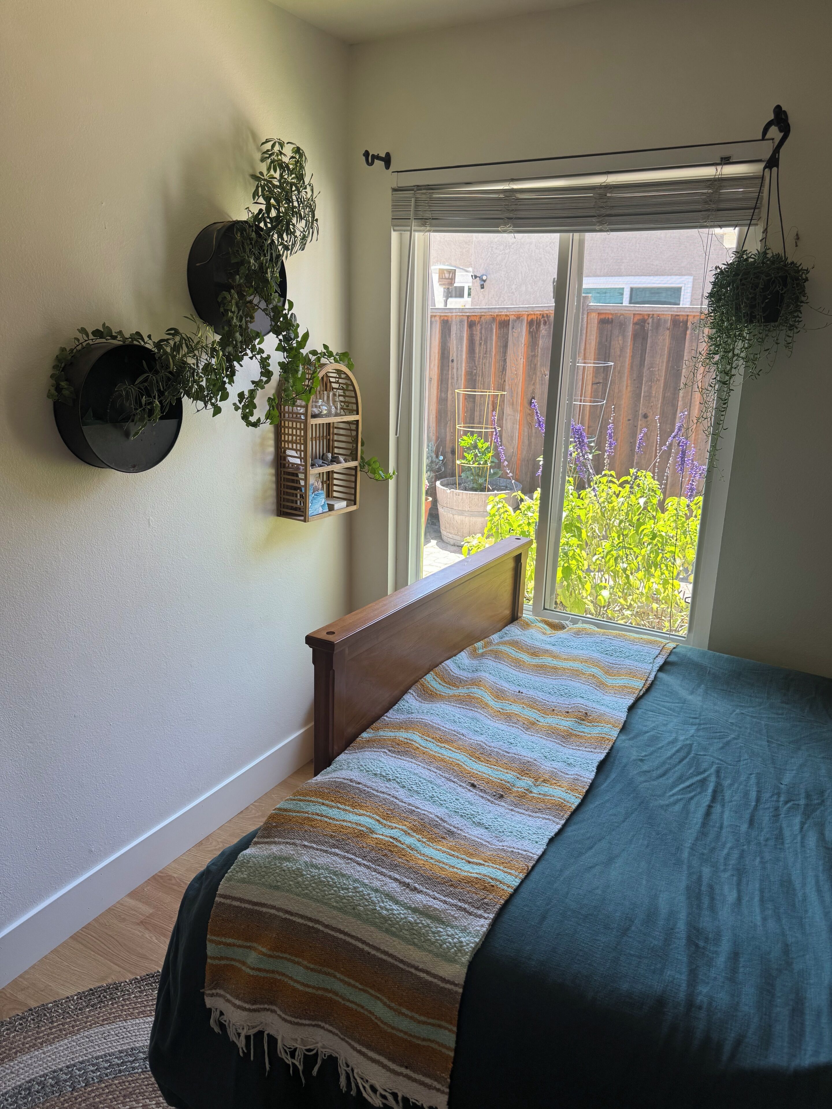 Un dormitorio con una cama, una ventana y vistas a un jardín.