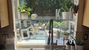 A kitchen with a built-in sink, a window overlooking a garden, and various kitchen items. - Private SLO Retreat - Bishop Peak Views, Near Cal Poly, Downtown & Wineries (San Luis Obispo)