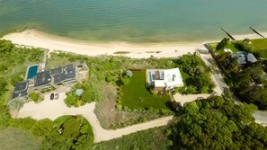 Vista aérea de una propiedad costera con piscina, una casa grande y una playa.