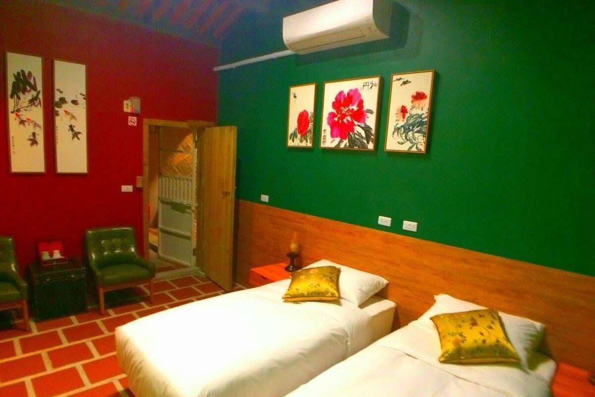 A hotel room with two beds, green walls, and artwork on the wall.