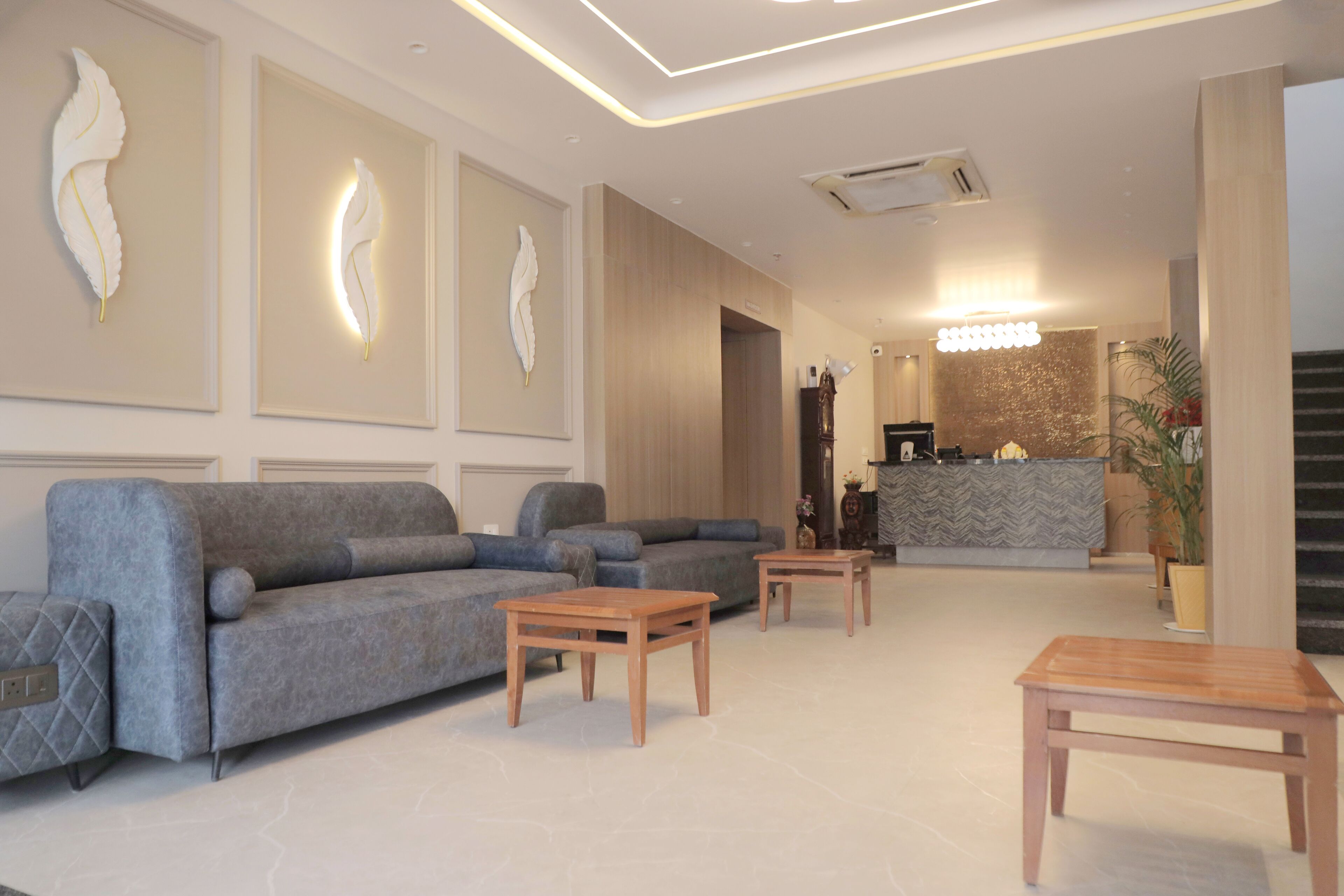 Un vestíbulo moderno con un sofá gris, mesas de madera y una recepción.
