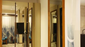 A hotel room with a large mirror, a TV, and a bathroom with a sink and mirror.