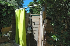 A wooden outdoor shower area with a green shower curtain, a hose, and a metal shower head. - Very nice, comfortable house, ideal location G0125 (Hourtin-Plage)