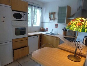 A kitchen with a microwave, oven, and dishwasher. There is a wooden countertop and a lamp with a stained glass shade.