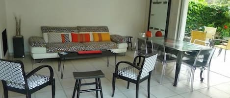 Un salon comprenant un canapé, une table basse, des fauteuils et une table à manger.