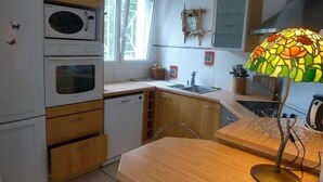 A compact kitchen with a dishwasher, oven, and a small window. - nicely furnished and comfortable, close to the beach (Hourtin-Plage)