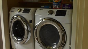 A laundry room with two front-loading washing machines and a basket on top. - Executive Suite with commanding views - Claudette Ct. (Victoria)