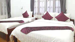 A hotel room with two single beds, each with white bedding and a purple throw blanket. The room has a wooden floor and white walls. - Eureka Villas Siem Reap (Siem Reap)