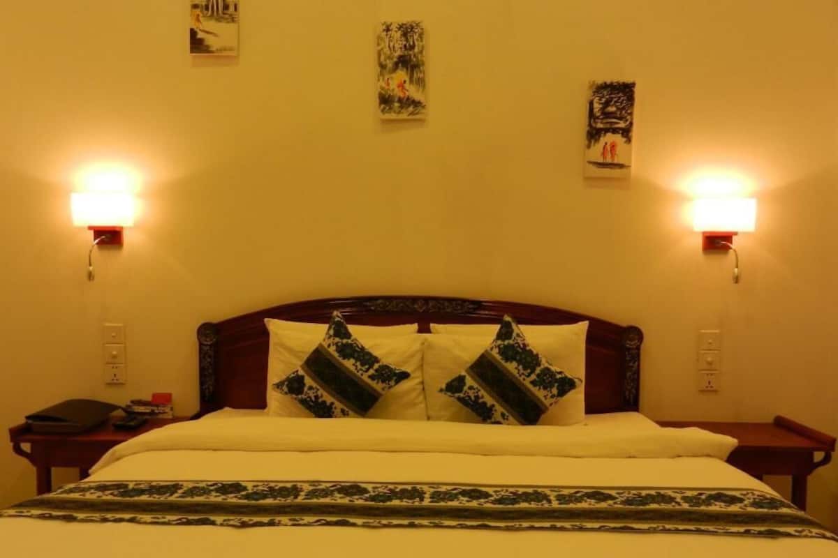 Una habitación de hotel con una cama, dos lámparas de noche y decoración en la pared.