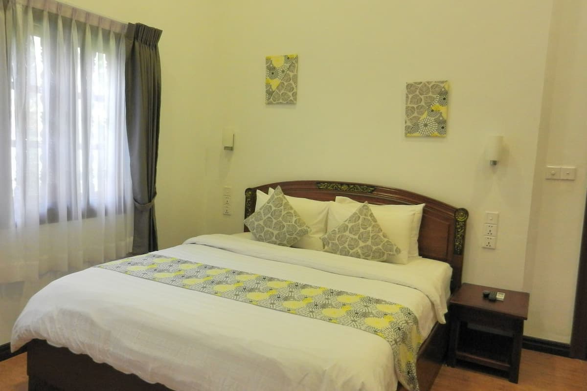 Una habitación de hotel con una cama, una mesita de noche y dos obras de arte colgadas en la pared.