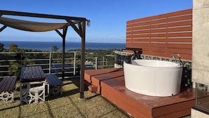 A rooftop patio with a hot tub, wooden tables, and a pergola. - The:MOVES-Musée Villa- (Nakijin)