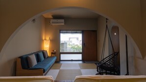 A room with a sofa, two beds, a hanging chair, and a view through a large window. - The:MOVES-Musée Villa- (Nakijin)