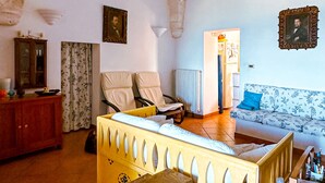 Ein Zimmer mit einer hohen, gewölbten Decke, einem Bett mit Holz-Kopfteil, einem kleinen Hocker, einem Holzschrank und einer Heizung.