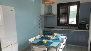 Una cucina compatta con un tavolo da pranzo, sedie, un frigorifero, un fornello e un forno a microonde.