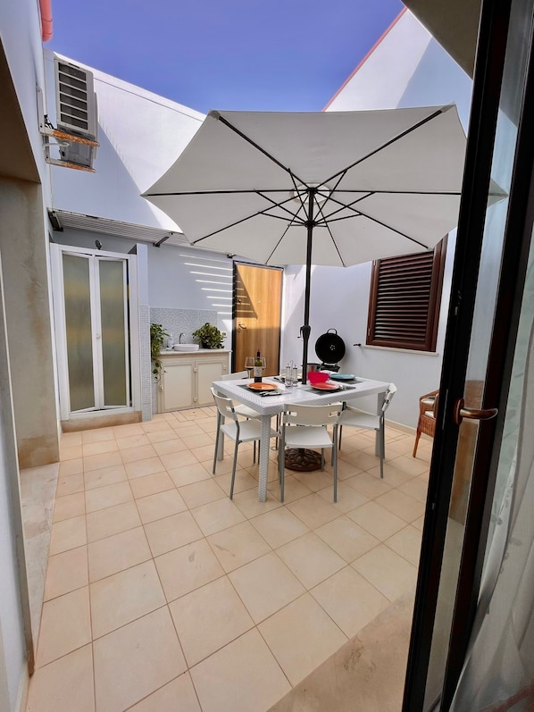 A patio area with a table and chairs, an umbrella, and a view of the house.