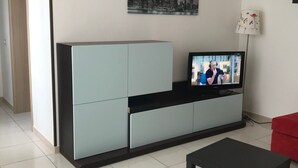 Un soggiorno moderno con un divano blu chiaro, un tavolino da caffè nero e una televisione su un mobile.