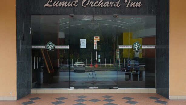 The entrance of Lumut Orchard Inn with a large glass facade, signage, and a visible street view. - Hotel O Hotel Orchard Inn (Lumut)