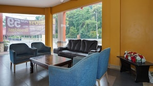 A seating area with a sofa and chairs, a table, and a ceiling fan. - Hotel O Hotel Orchard Inn (Lumut)