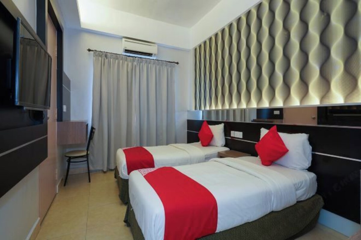 A hotel room with two beds, a TV, a desk, and a wall with a textured design.