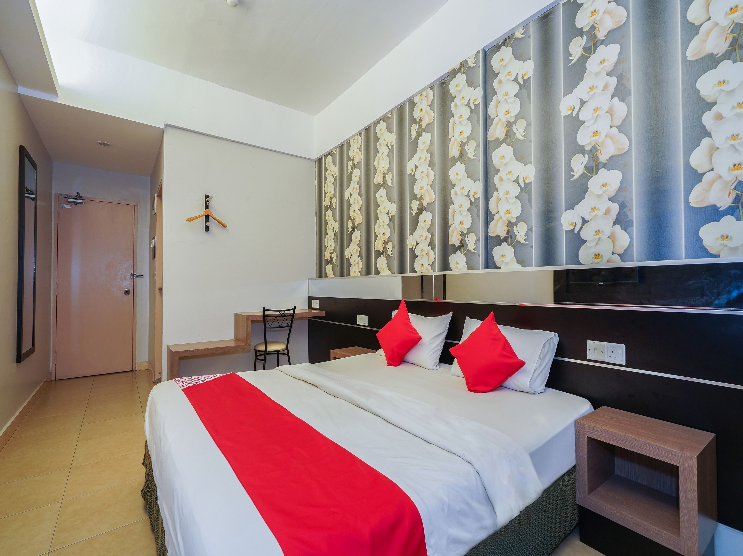A hotel room with a bed, a desk, a chair, and a wardrobe.